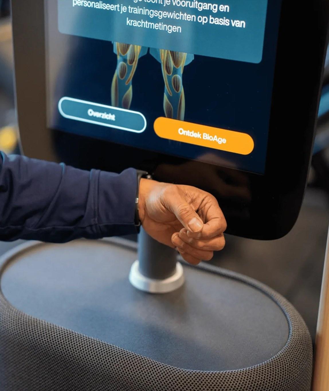 Een lid meldt zich met zijn horloge aan bij het scherm van een EGYM-toestel